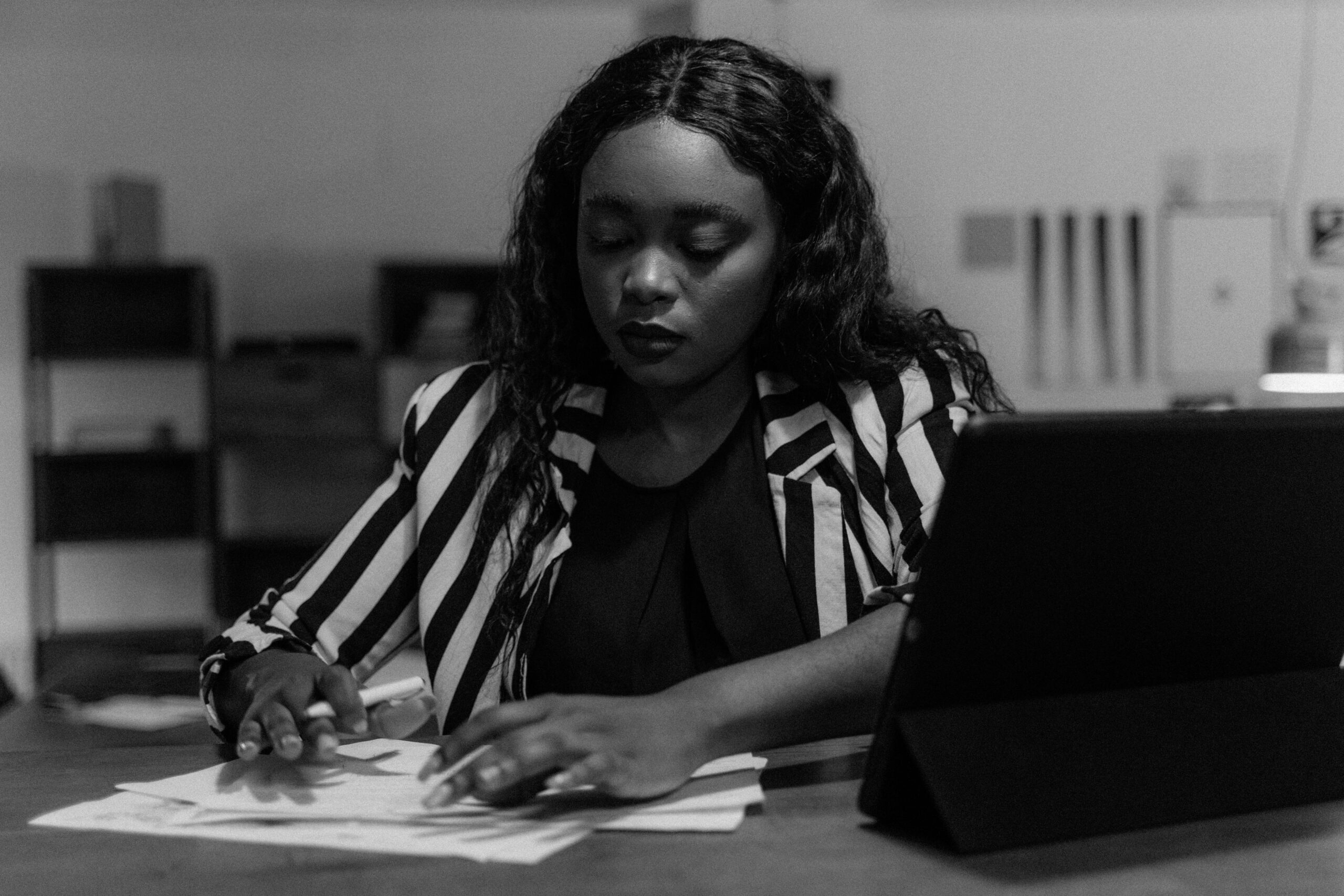 Black and white image of a businesswoman working diligently at her desk.