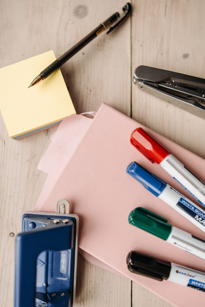 A creatively arranged collection of office supplies including markers, stapler, and sticky notes.